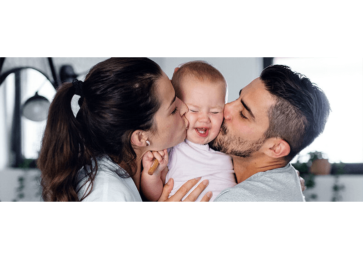 mother and father kissing baby